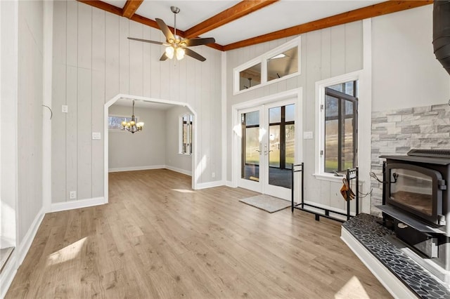 living area with light wood-style floors, arched walkways, beam ceiling, and a wood stove