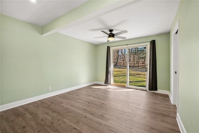 spare room with ceiling fan, beam ceiling, baseboards, and wood finished floors