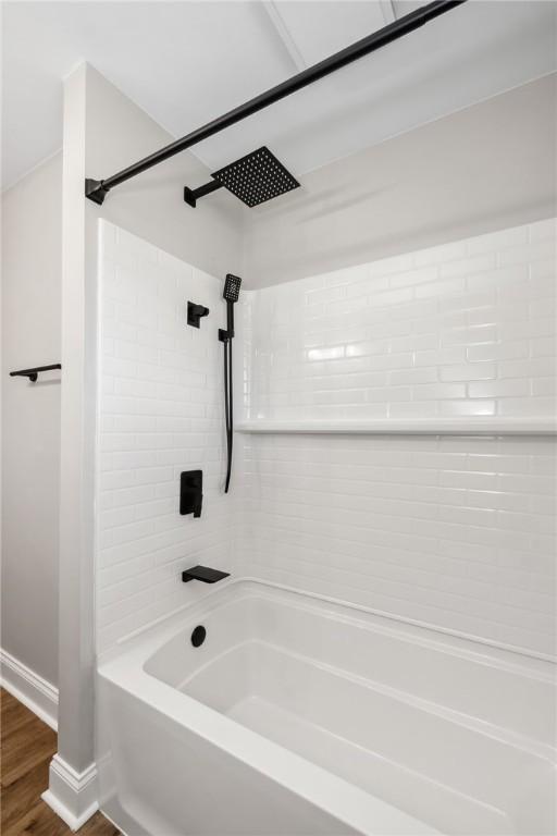 bathroom with shower / bath combination, wood finished floors, and baseboards