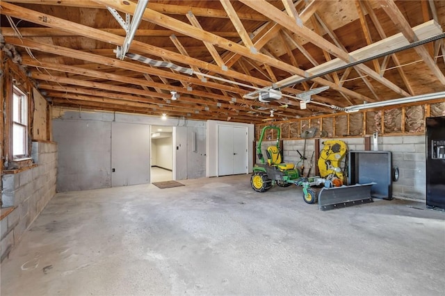 garage with a garage door opener and concrete block wall