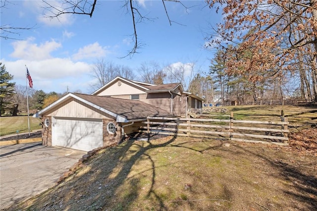 view of home's exterior featuring a garage, fence, driveway, a lawn, and roof with shingles