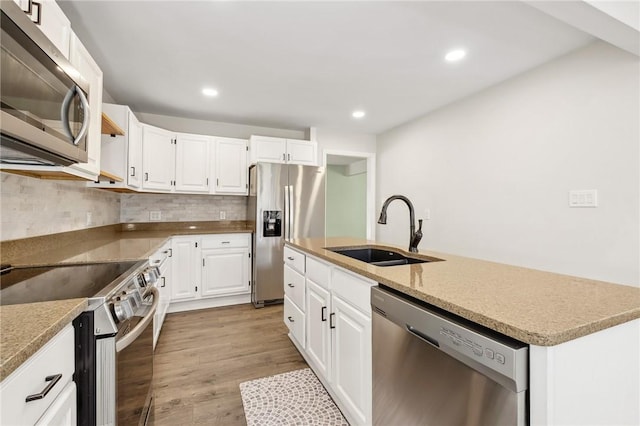 kitchen with stainless steel appliances, tasteful backsplash, light wood-style floors, a kitchen island with sink, and a sink