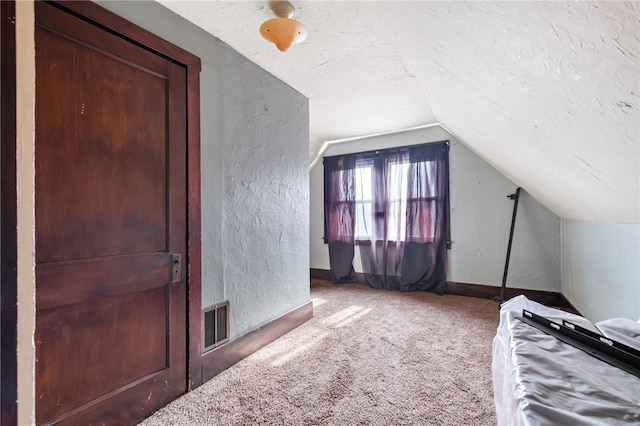 additional living space with a textured ceiling, a textured wall, and carpet flooring