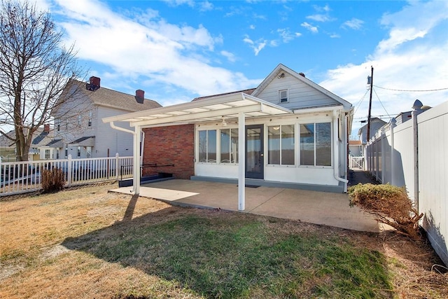 back of property featuring a lawn, a patio, a sunroom, a fenced backyard, and brick siding