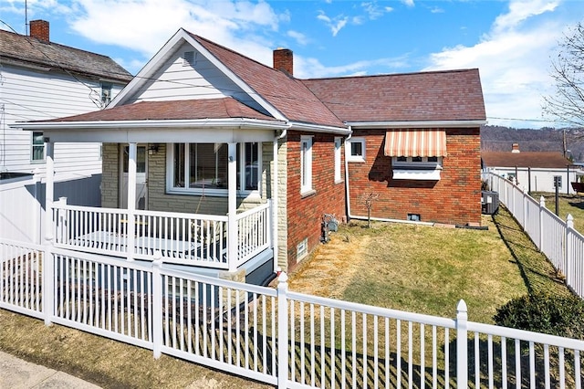 bungalow featuring brick siding, a fenced backyard, crawl space, a porch, and a front yard