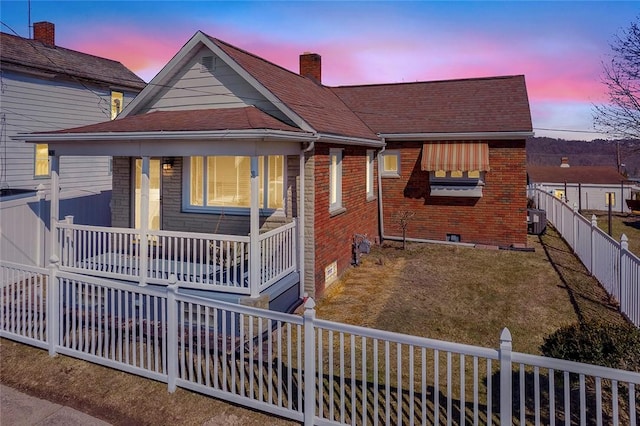 view of front of property featuring central AC unit, a fenced backyard, crawl space, covered porch, and brick siding