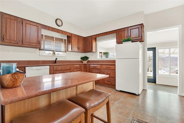 kitchen with light stone counters, a peninsula, white appliances, a breakfast bar, and a sink