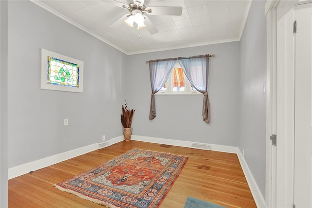 empty room featuring ornamental molding, visible vents, baseboards, and wood finished floors