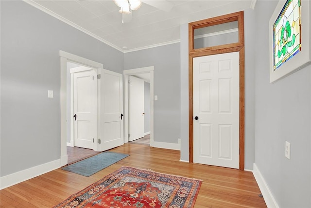 interior space featuring ornamental molding, light wood-type flooring, and baseboards