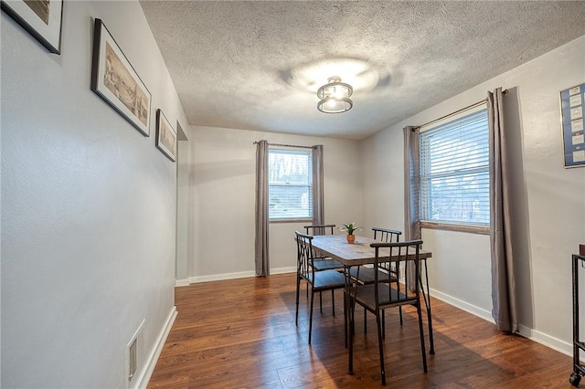 dining space with a textured ceiling, dark wood-type flooring, and baseboards