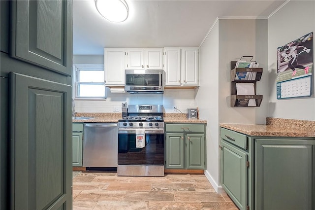 kitchen featuring stainless steel appliances, white cabinetry, light countertops, light wood-type flooring, and green cabinetry