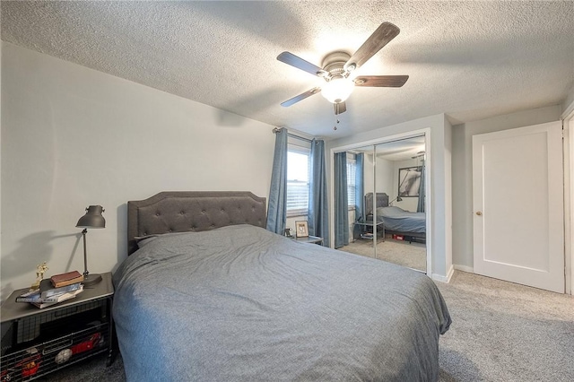 bedroom featuring a textured ceiling, a closet, a ceiling fan, and light colored carpet