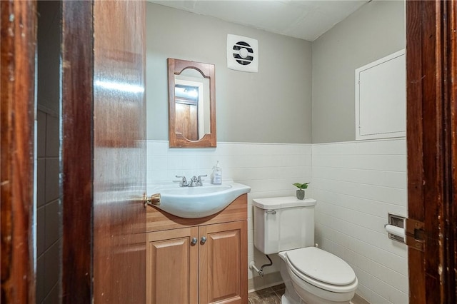 half bath featuring wainscoting, vanity, and toilet