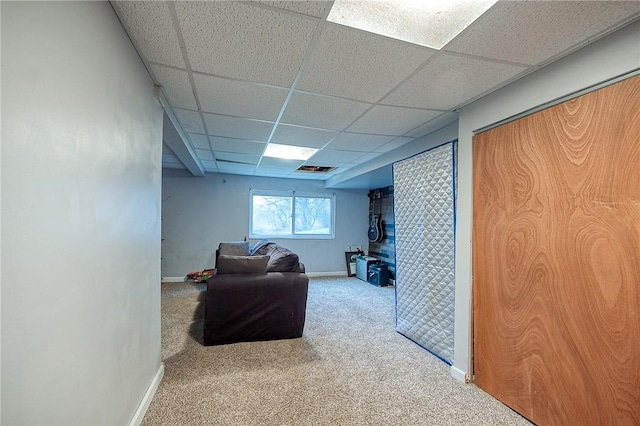 carpeted living area with baseboards and a drop ceiling