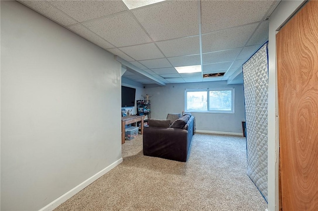 carpeted living room featuring a drop ceiling and baseboards