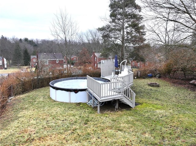 view of yard featuring a fire pit, a covered pool, a wooden deck, and fence