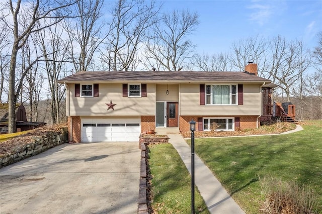 raised ranch featuring driveway, a chimney, an attached garage, a front yard, and brick siding