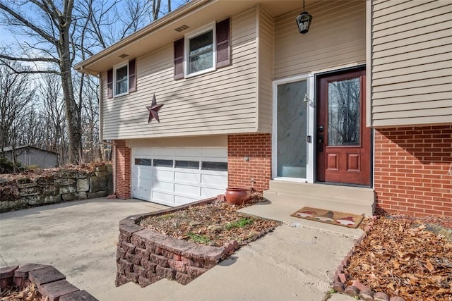 property entrance with an attached garage, concrete driveway, and brick siding