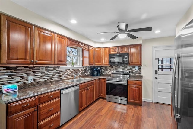 kitchen with dark wood-type flooring, stainless steel appliances, a sink, and brown cabinetry