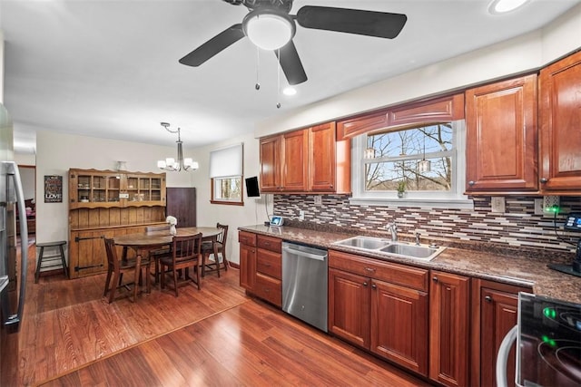 kitchen featuring dark wood finished floors, dark countertops, electric range oven, stainless steel dishwasher, and a sink