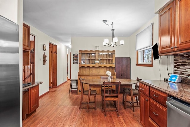 dining room featuring a chandelier, light wood-style flooring, and baseboards