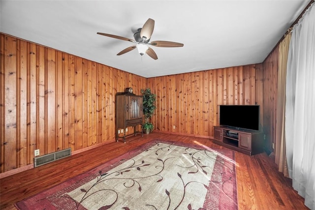 unfurnished living room featuring a ceiling fan, visible vents, baseboards, and wood finished floors