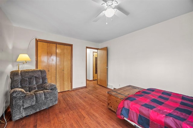 bedroom featuring a closet, visible vents, a ceiling fan, wood finished floors, and baseboards