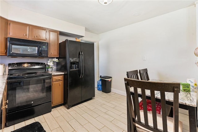 kitchen featuring brown cabinets, black appliances, baseboards, and light countertops