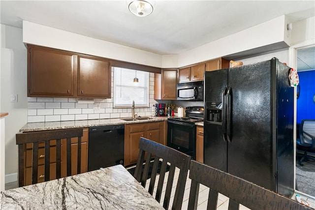 kitchen with black appliances, tasteful backsplash, light stone counters, and a sink