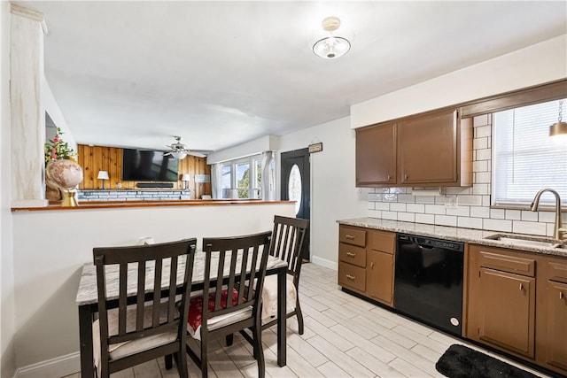 kitchen with black dishwasher, tasteful backsplash, light wood-style flooring, a sink, and baseboards