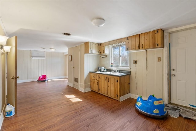 kitchen featuring light wood finished floors, visible vents, baseboards, and a sink