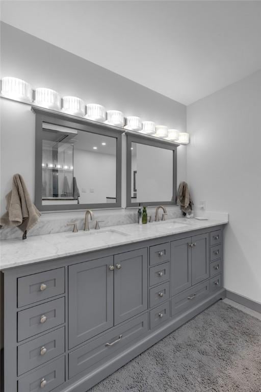 bathroom with a sink, baseboards, and double vanity