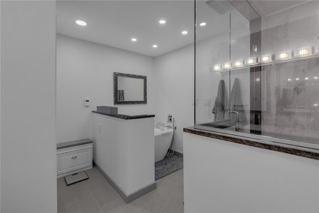 bathroom featuring a soaking tub, baseboards, a sink, and recessed lighting