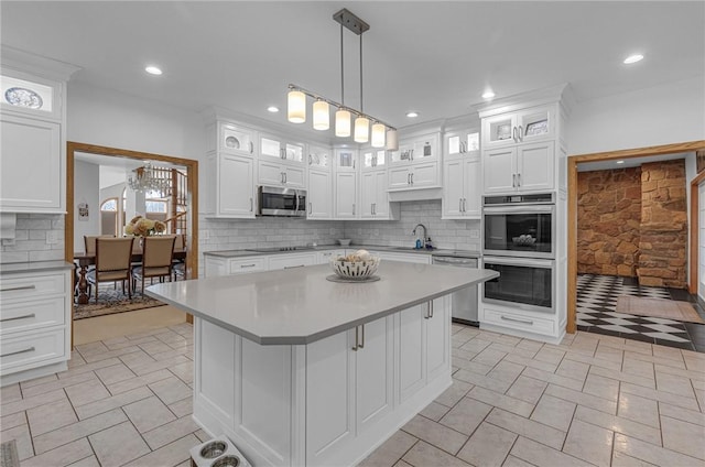 kitchen featuring stainless steel appliances, white cabinets, light countertops, and a sink