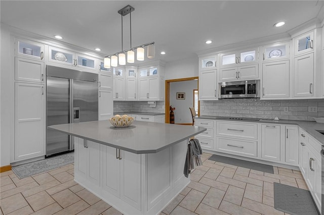 kitchen featuring tasteful backsplash, white cabinets, a kitchen island, stainless steel appliances, and pendant lighting