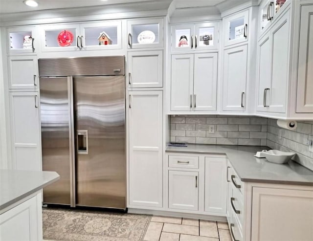 kitchen with light countertops, built in refrigerator, glass insert cabinets, and white cabinets