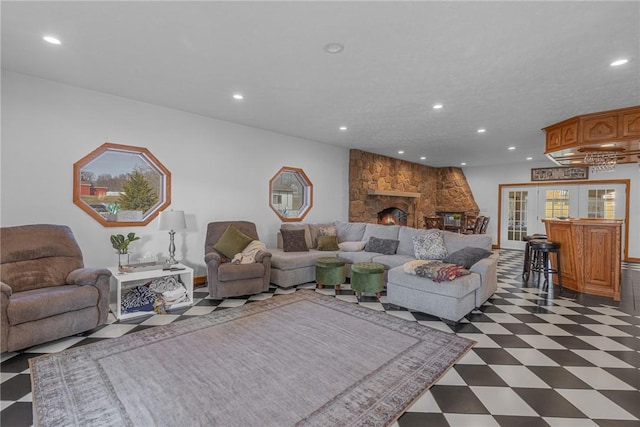 living room with dark floors, a stone fireplace, and recessed lighting