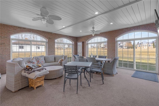 sunroom featuring wood ceiling, a ceiling fan, and a healthy amount of sunlight