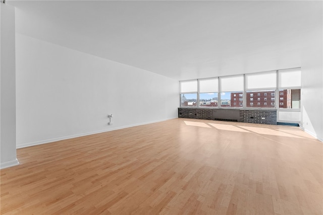 unfurnished living room featuring baseboards, a city view, and wood finished floors