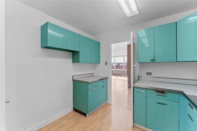 kitchen featuring light wood-style flooring, baseboards, and light countertops