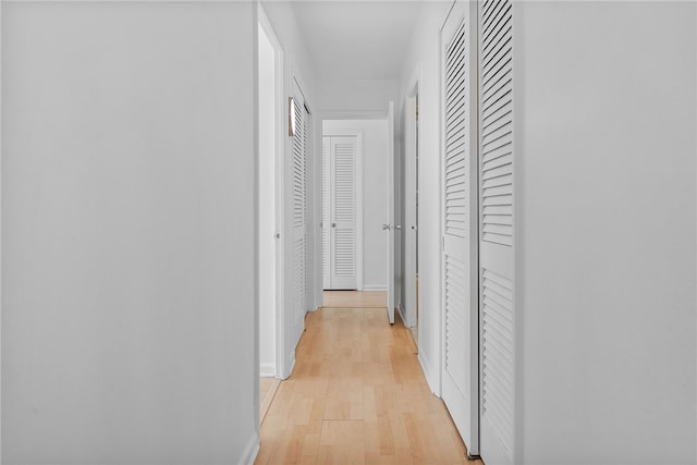 hallway featuring light wood-type flooring and baseboards