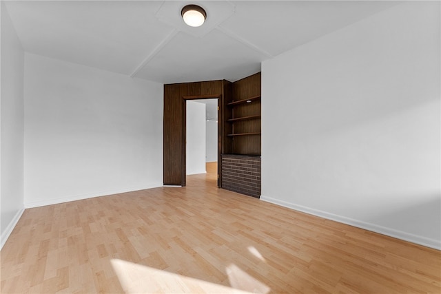 spare room with built in features, baseboards, and wood finished floors