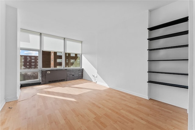 spare room featuring floor to ceiling windows, baseboards, and wood finished floors