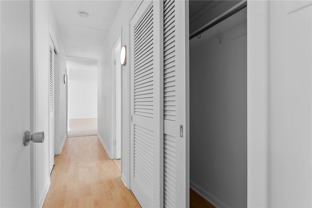 hallway featuring baseboards and light wood-style floors