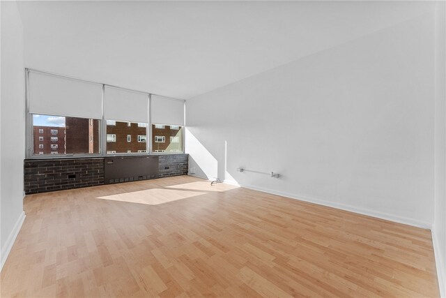 unfurnished living room with a wealth of natural light, baseboards, and wood finished floors