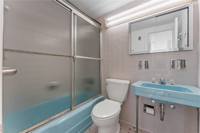 full bathroom with tile patterned flooring, toilet, shower / bath combination with glass door, a sink, and tile walls