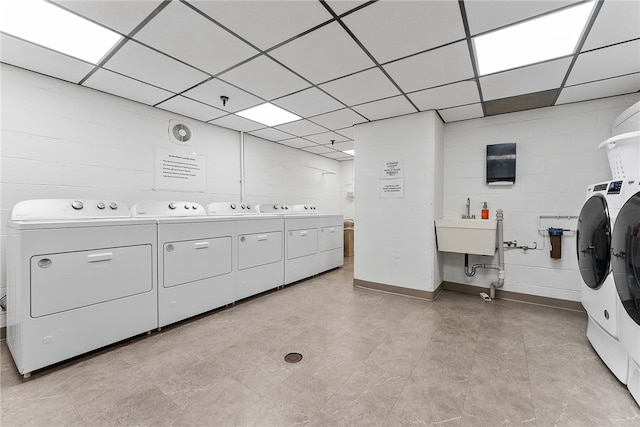 shared laundry area featuring concrete block wall, independent washer and dryer, and a sink