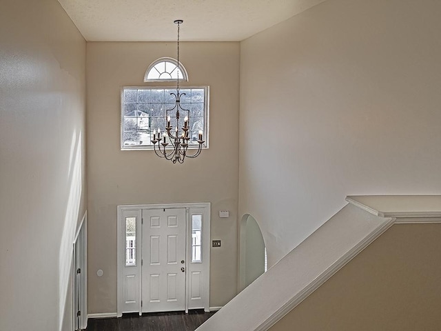 entryway featuring dark wood-type flooring and an inviting chandelier