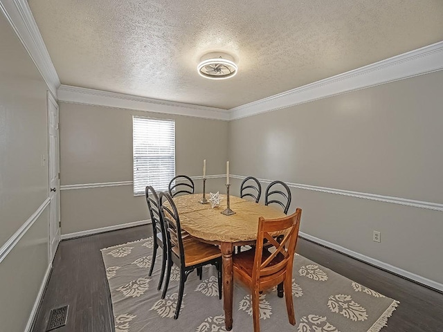 dining space with visible vents, ornamental molding, a textured ceiling, wood finished floors, and baseboards