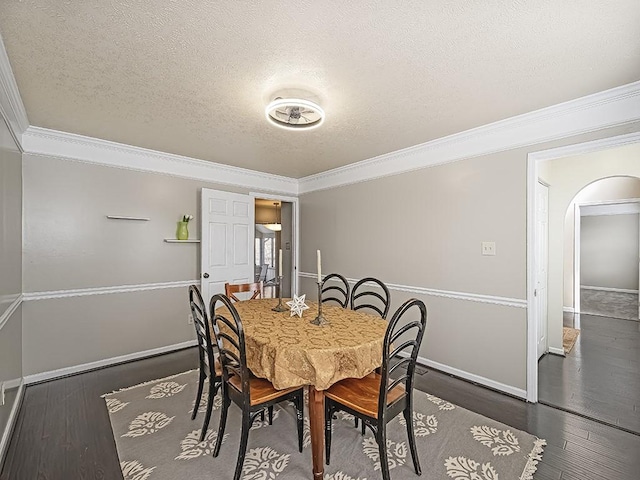 dining area featuring baseboards, arched walkways, ornamental molding, wood finished floors, and a textured ceiling